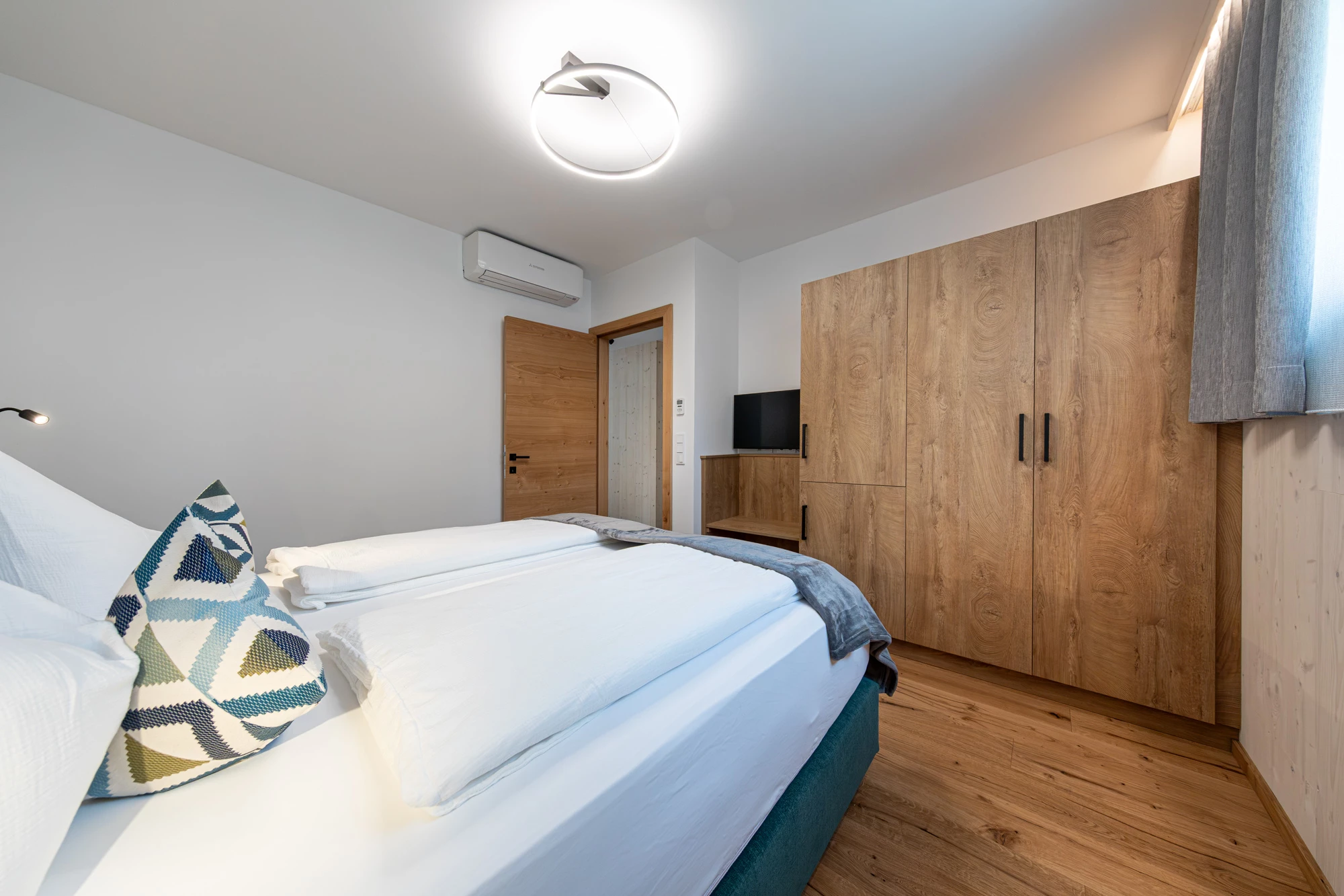 Doppelbett mit Blick auf Kleiderschrank und TV
