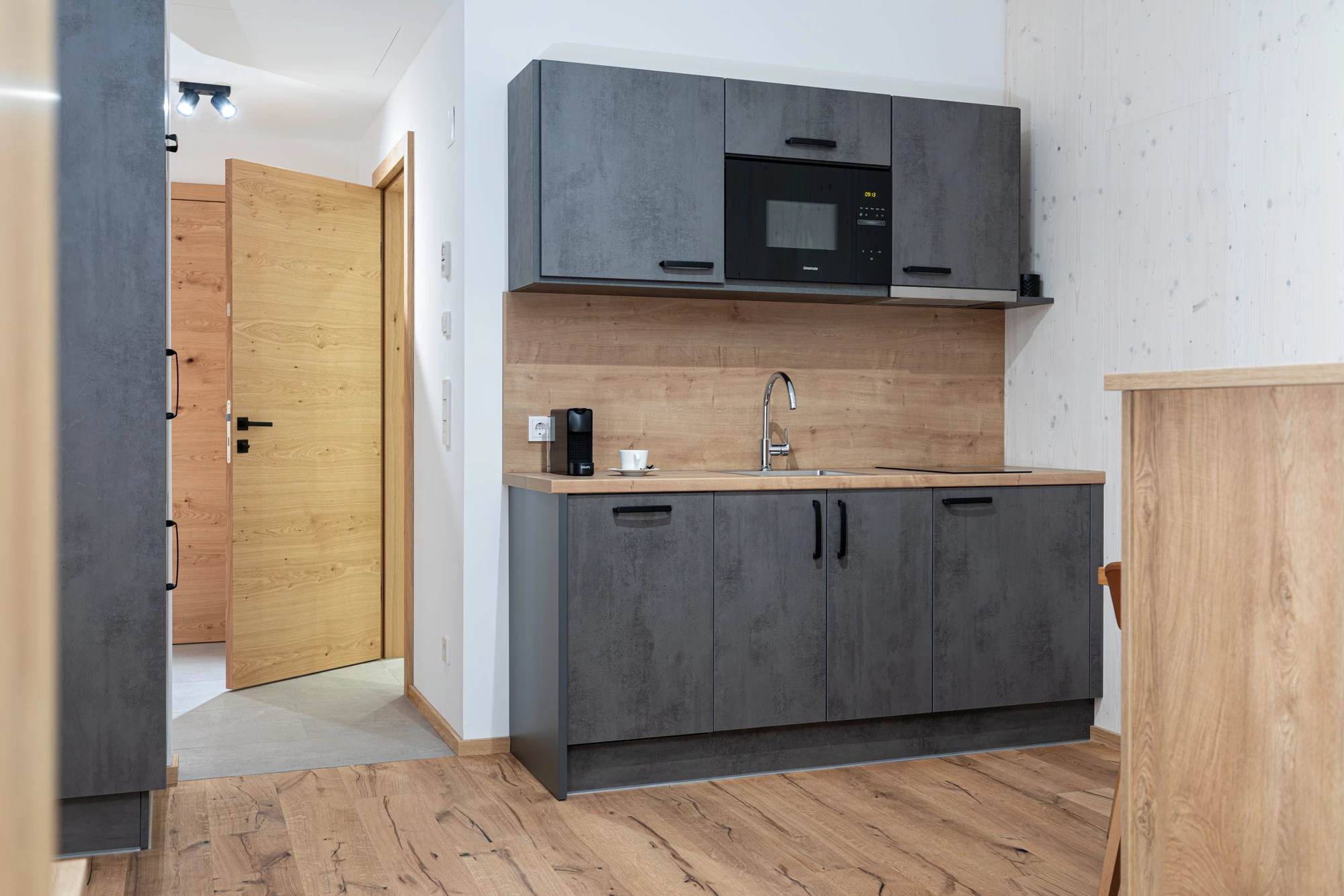 Küchenzeile mit Mikrowelle, Spüle und Kaffeemaschine, Blick in den Flur