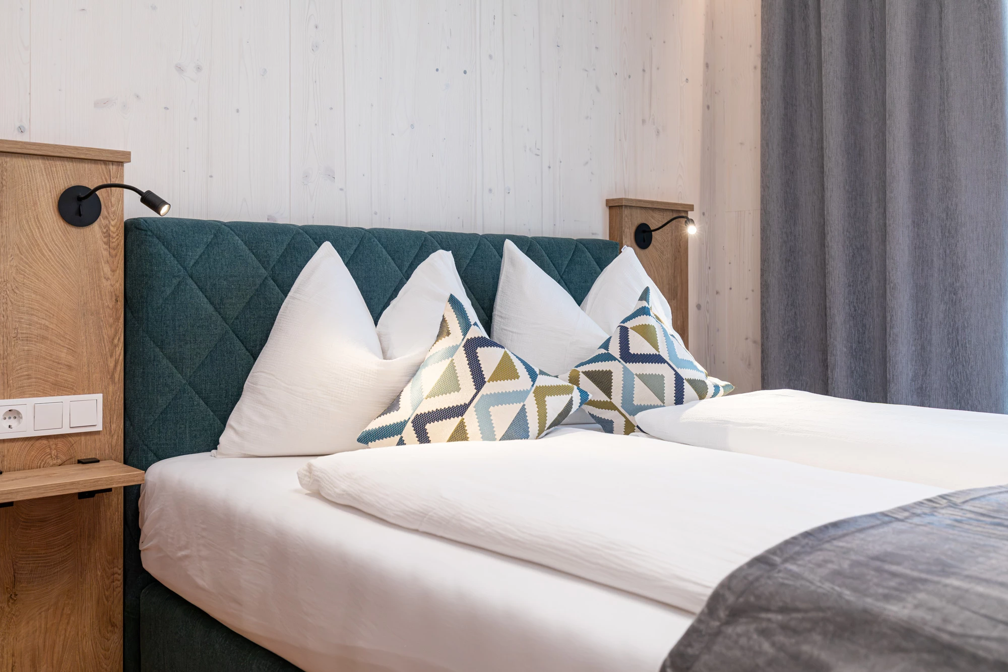 Doppelbett mit Leselampen und gemusterten Zierkissen