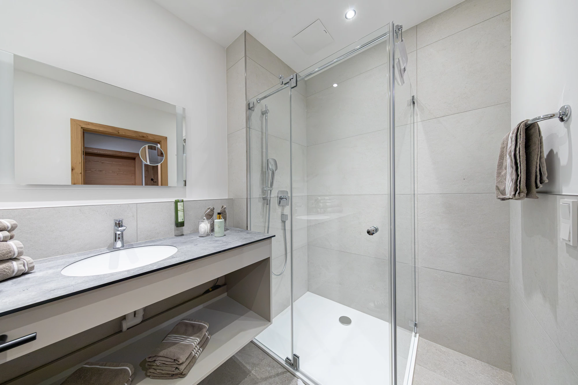 Badezimmer mit Glasdusche und Waschtisch mit Spiegel