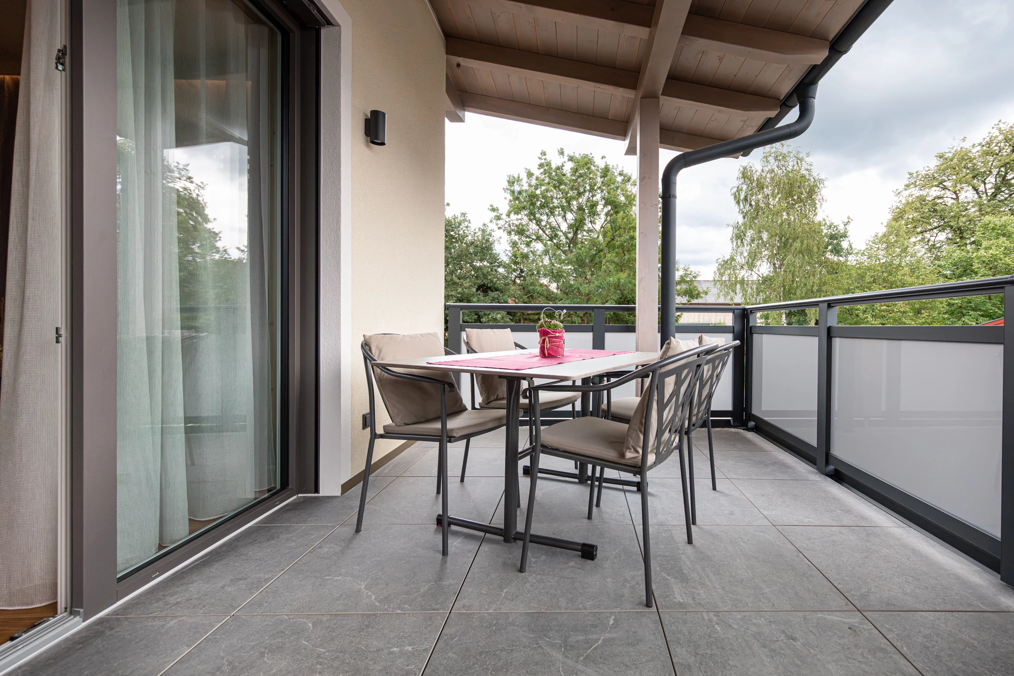 Überdachter Balkon mit Tisch und vier Stühlen