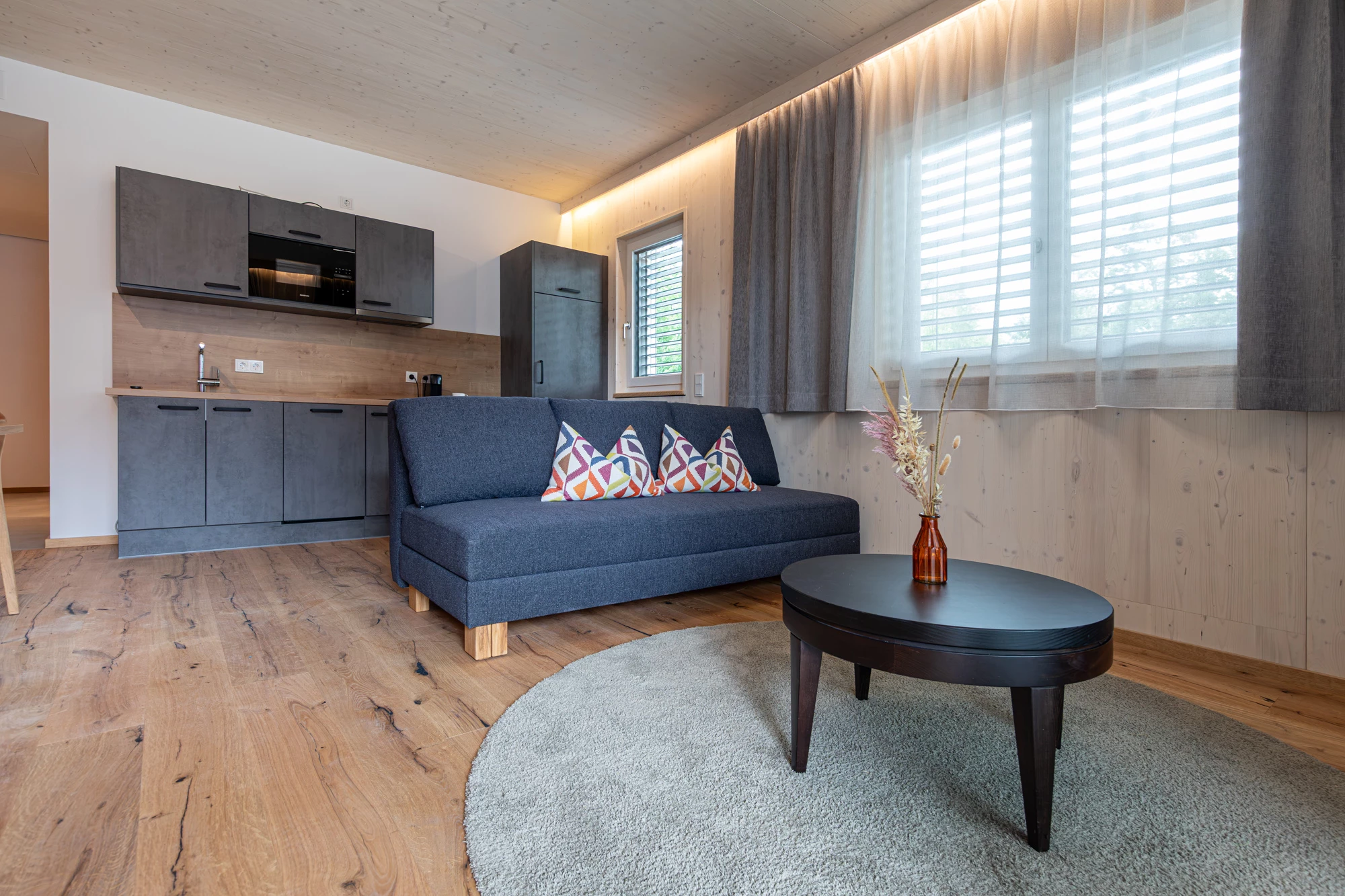 Sofa mit bunten Kissen vor der Küchenzeile