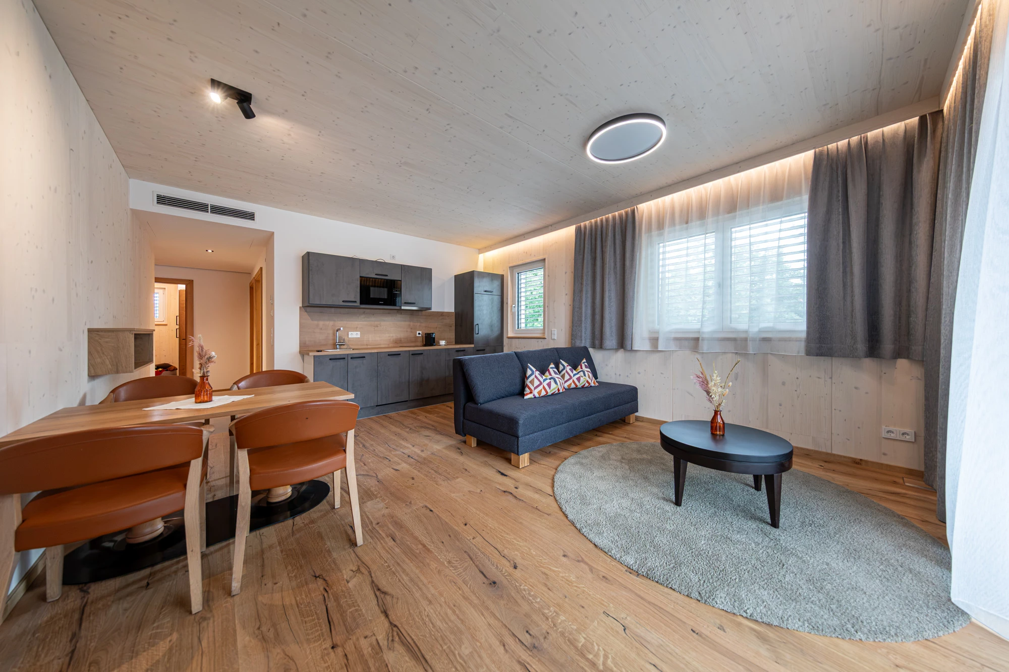 Wohnbereich mit Esstisch, Küchenzeile, Sofa und rundem Couchtisch